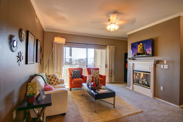 Living room with carpet, plush seating, fireplace, TV, and sliding door to balcony.