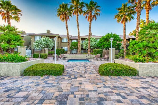 Pool area with spa, lounge chairs, lush landscaping, and tall palms.