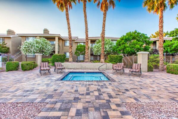 Pool area with spa, lounge chairs, lush landscaping, and tall palms.
