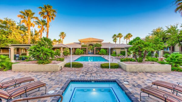 Pool area with spa, lounge chairs, lush landscaping, and tall palms.