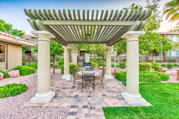 Outdoor gazebo with stone paver patio, dining table, and built in BBQ grill.