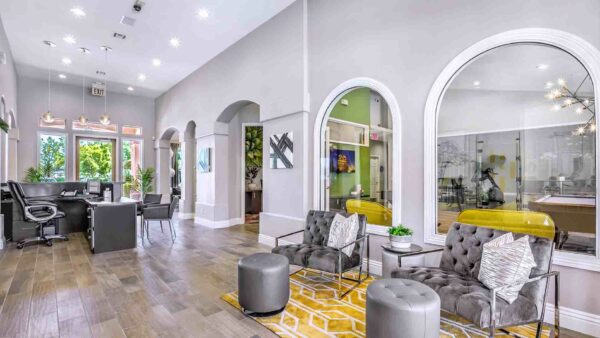 Clubhouse with plush seating, large windows, computer desk with chairs, and artwork.
