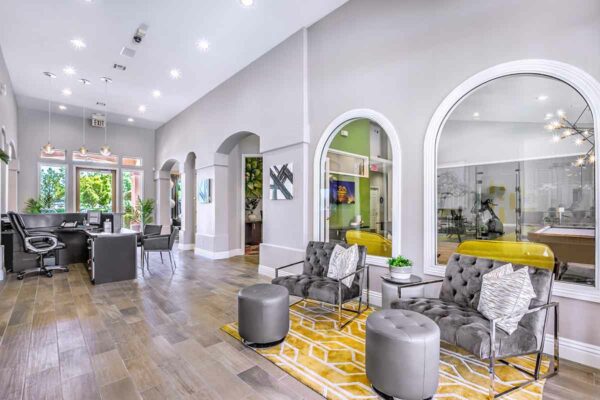 Clubhouse with plush seating, large windows, computer desk with chairs, and artwork.