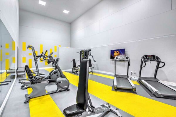 Fitness center with colorful accents, cardio machines, weight equipment, and TV.