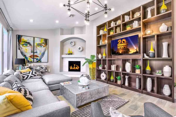 Clubroom with plush couch, fireplace, shelves with decor and TV, and large artwork.