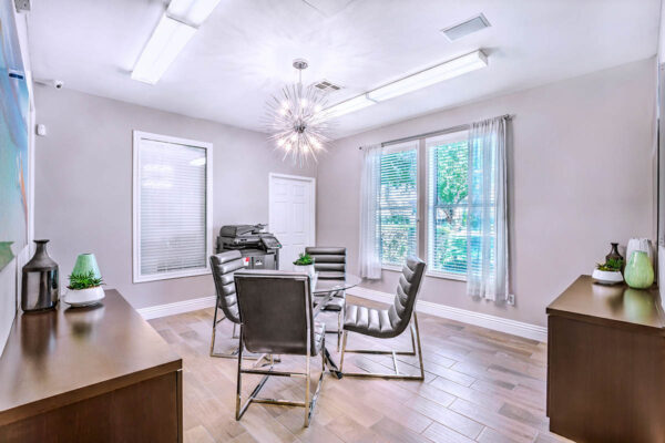 Lounge with table and chairs, drawers with decor, large printer, and large window.