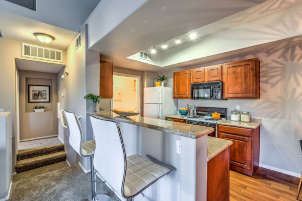 Kitchen with wood style floor, wood cabinets, stone counters, and white fridge.