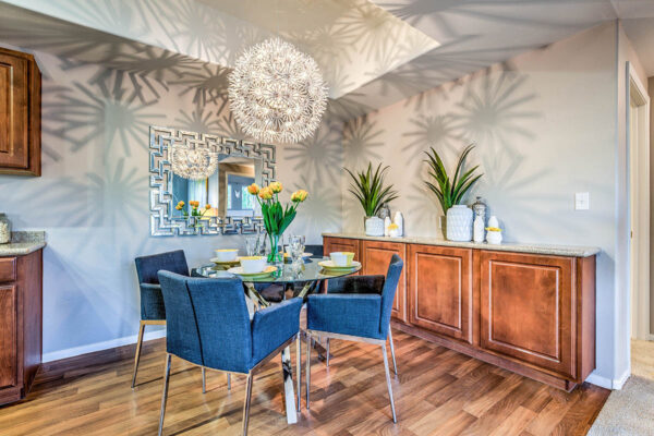 Dining area with wood style floor, large cabinets, round glass table with chairs, and light fixture.