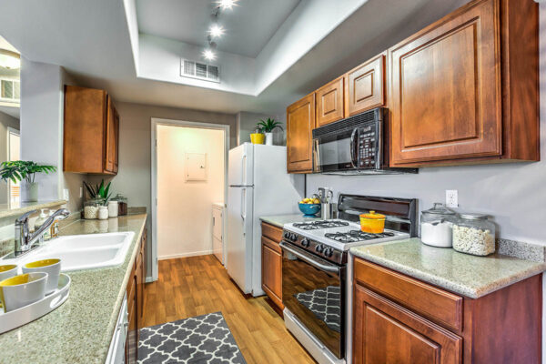 Kitchen with wood cabinets, stone counters, white appliances, and laundry closet.