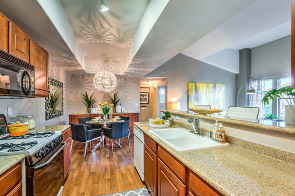 Kitchen with wood cabinets, stone counters, white appliances, and dining area.