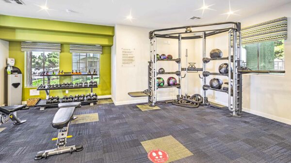 Fitness center with weight equipment and large windows.