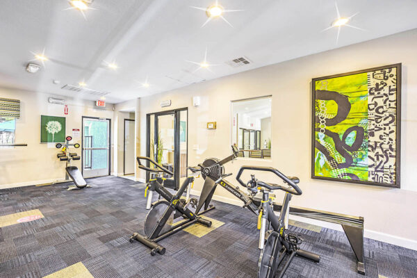 Fitness center with cardio machines and framed artwork.