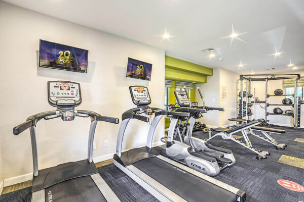 Fitness center with cardio machines, weight equipment, and TVs.