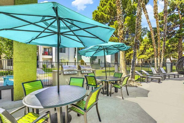 Outdoor lounge with dining tables, umbrellas, lounge chairs, and built in BBQ grills.