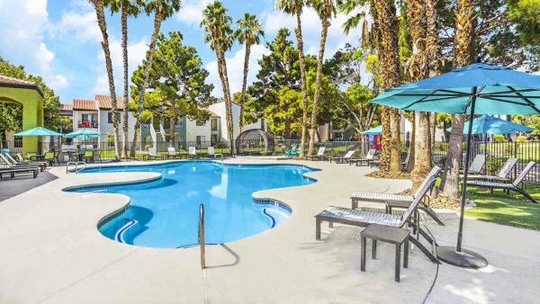 Pool area with lounge chairs, gazebos, lush landscaping, and tall palms.