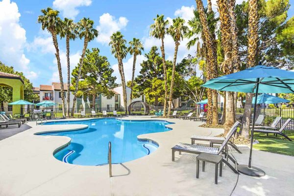 Pool area with lounge chairs, gazebos, lush landscaping, and tall palms.