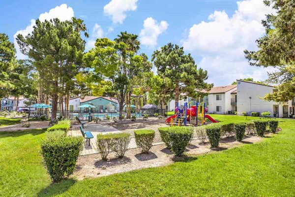 Outdoor playground with paver patio, bench seating, and lush landscaping.