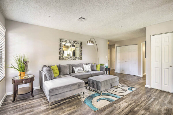 Living room with plush furniture, standing lamp, framed mirror, and french doors to closets.