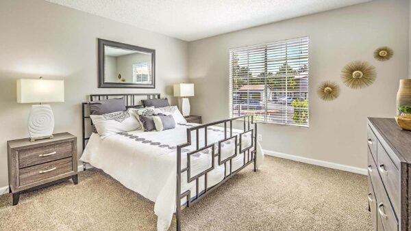 Bedroom with carpet, plush bed, bedside chests with lamps, and large window.