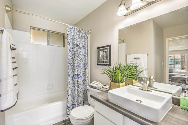 Bathroom with white cabinets, sink basin, large mirror, and tiled shower tub.