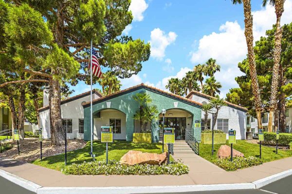 The Grove apartments entrance with lush landscaping, tall palms, and ample parking.