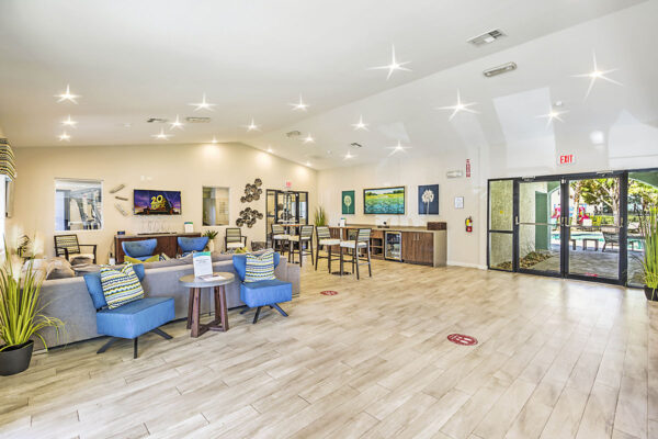 Clubroom with tile floor, plush seating, vaulted ceiling, and entry door.