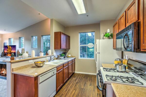 Kitchen with wood floor and cabinets, stone counters, and white appliances.