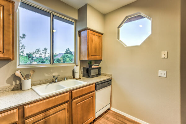 Kitchen with wood floor and cabinets, stone counters, white appliances, and octagonal window in apartment in Summerlin Las Vegas