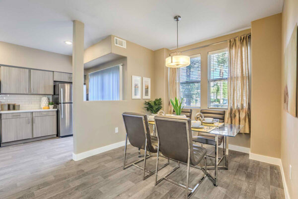 spacious dining room in Summerlin apartment with wood floor, glass table, leather chairs, and large windows.