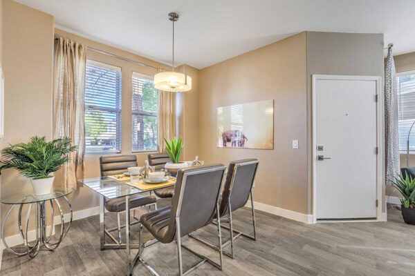 Summerlin apartment dining room with wood floor, glass table, leather chairs, and large windows.