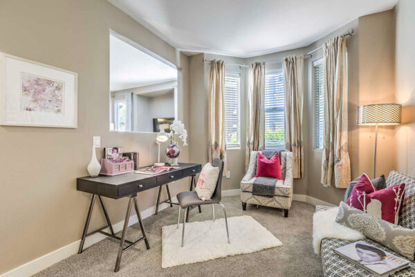Luxury Summerlin apartment office with carpet, plush bench seat, desk with chair, and large windows.
