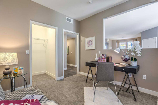 Large Summerlin apartment office with carpet, plush bench seat, desk with chair, and spacious closet.