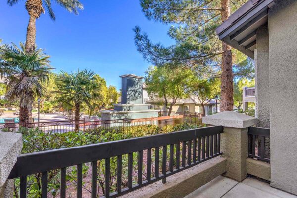 Balcony with metal railings overlooking lushly landscaping pool area with tall palms.