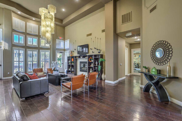 Clubroom with wood floor, leather seating, shelves with decor, TV, and large windows.
