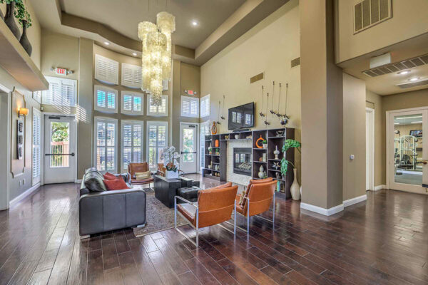 Clubroom with wood floor, leather seating, shelves with decor, TV, and large windows.