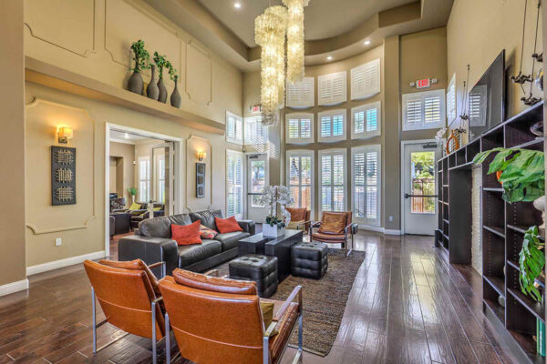Clubroom with wood floor, leather seating, shelves with decor, TV, and large windows.