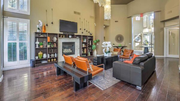 Clubroom with wood floor, leather seating, shelves with decor, TV, and large windows.