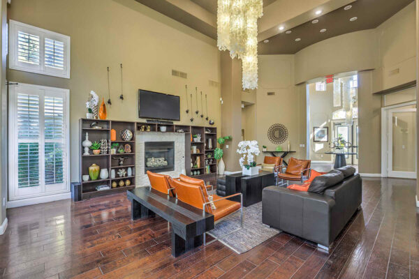 Clubroom with wood floor, leather seating, shelves with decor, TV, and large windows.