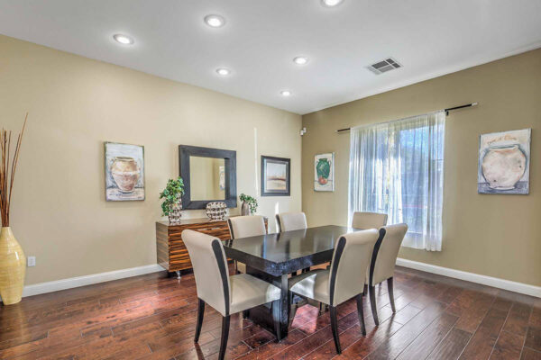 Meeting room with wood floor, conference table with chairs, console with decor, and large mirror.