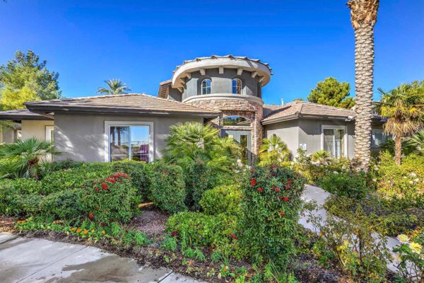 Tuscany apartment clubhouse with classic architecture, lush landscaping, and tall palm trees.