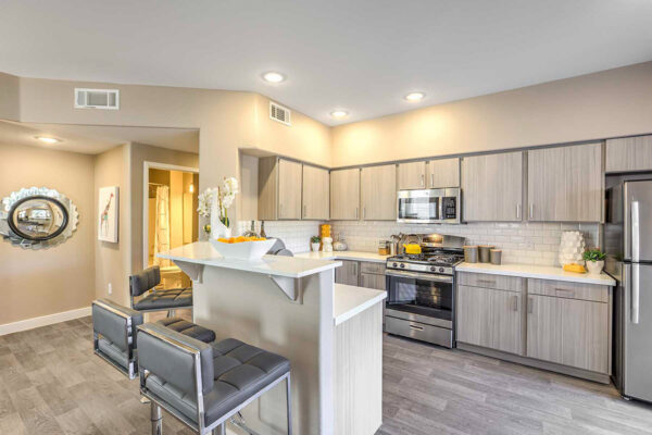 Kitchen in Summerlin apartment with wood floor and cabinets, light counters, stainless steel appliances, and breakfast bar.