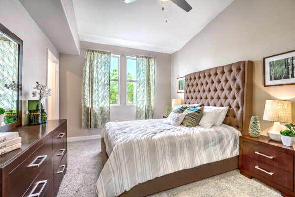 large bedroom in Summerlin apartment with high ceilings, large windows, dresser and plush bed