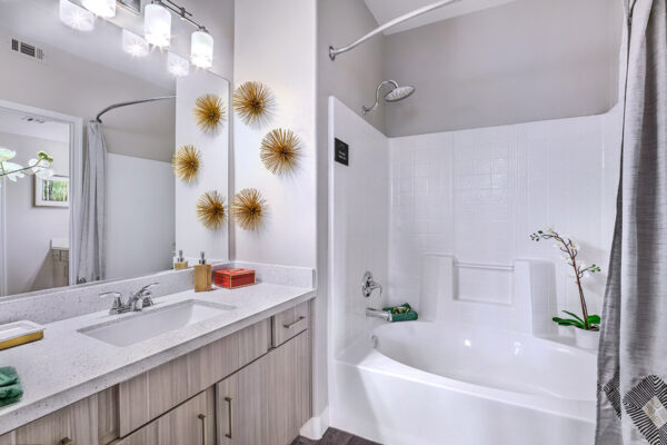 Bathroom in apartment in summerlin with shower tub. wood cabinets, light counters, and large mirror,