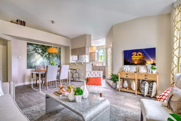 inviting living room in summerlin apartment with couches, mounted TV and door to one bedroom