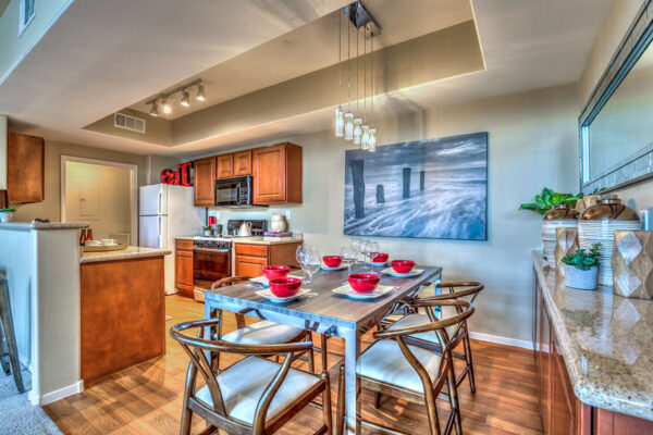 Dining room with wood floor, metal dining table with chairs, glass light fixture, and large artwork.