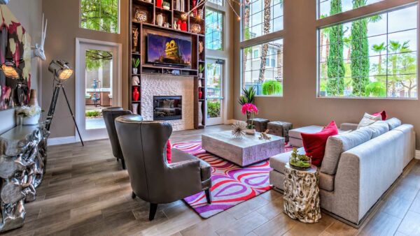 Clubroom with plush seating, large windows, fireplace, TV, and shelves with decor.