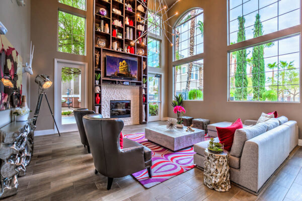 Clubroom with plush seating, large windows, fireplace, TV, and shelves with decor.