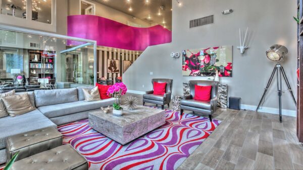 Clubroom with plush seating, colorful rug, large tripod lamp, and eclectic artwork.