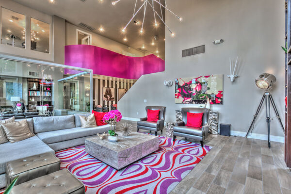 Clubroom with plush seating, colorful rug, large tripod lamp, and eclectic artwork.