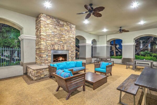 Indoor/outdoor lounge with built in BBQ grills, picnic table, couch, and fireplace.